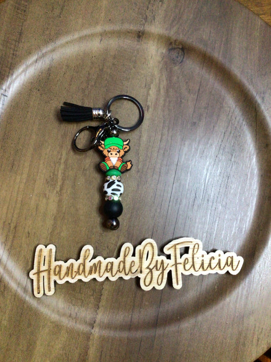 Cow print cow with green hat keychain
